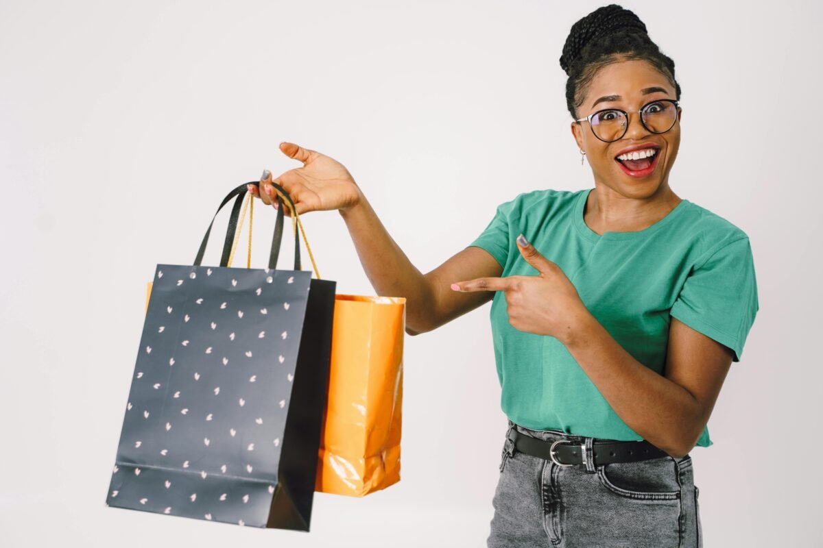 Smiling woman in a studio holding colorful shopping bags, excited about her purchases.