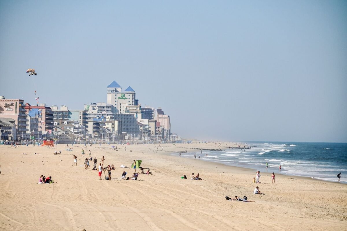 People enjoying a sunny day at a busy beach near waterfront hotels and buildings.